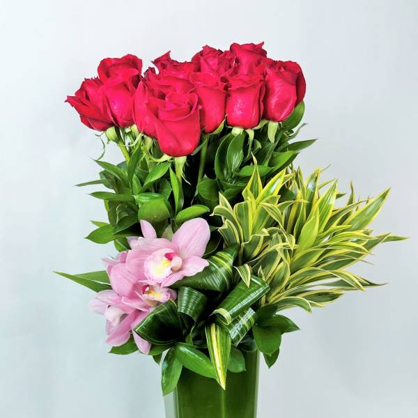 Red roses and pink orchids in a tall glass vase