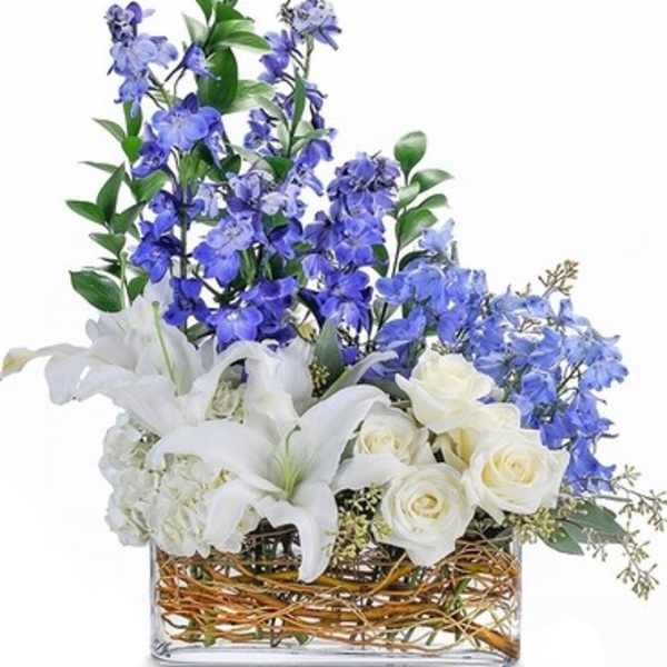 White lilies and roses with blue flowers in a glass vase