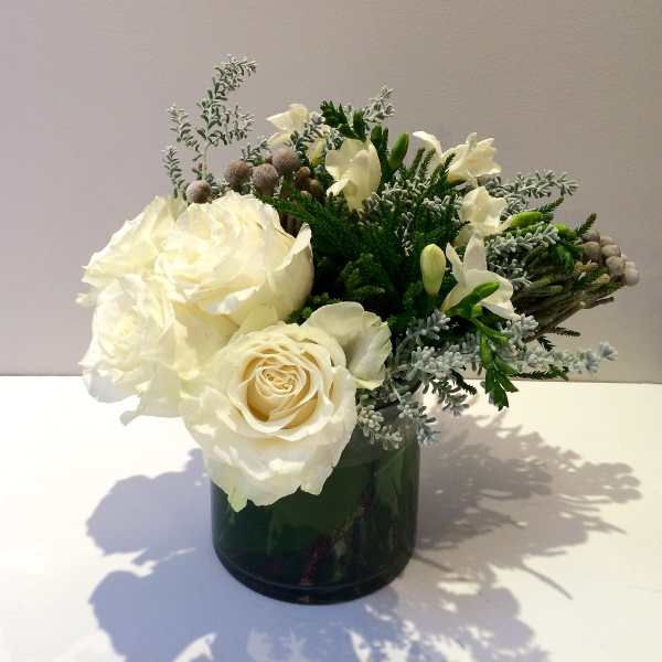 White roses and small white flowers in a dark glass vase
