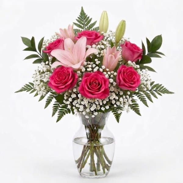 Pink roses and lilies arranged in a clear glass vase