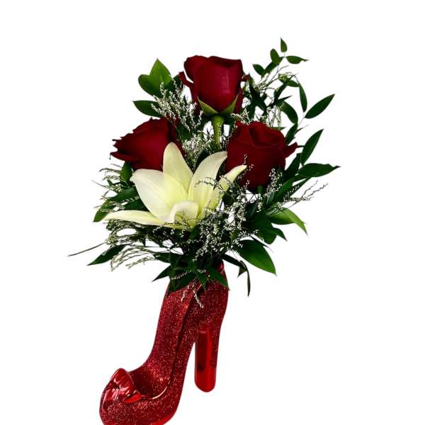Red roses and a white lily arranged in a glittery red high-heel vase