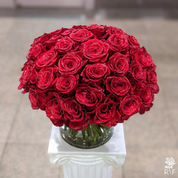 Round bouquet of red roses in a clear glass vase