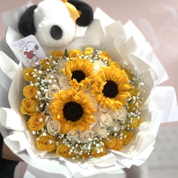 Bouquet of yellow sunflowers and pale roses with a plush panda topper