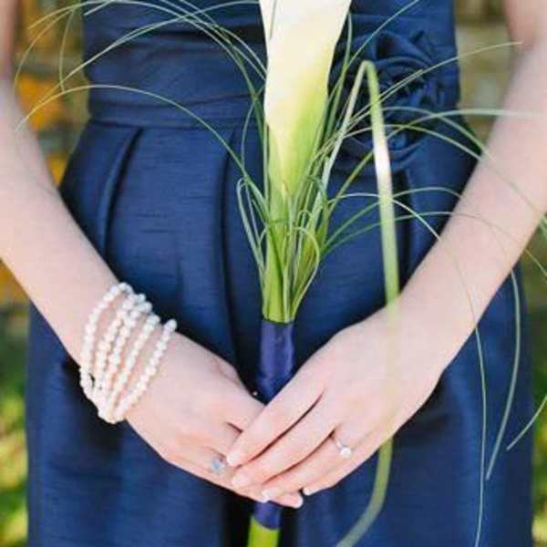 Woman holding a white calla lily bouquet with long grass accents