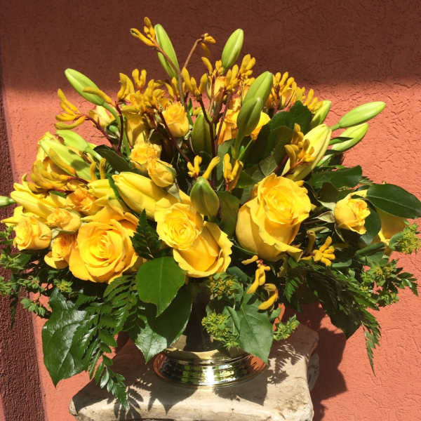 Yellow roses and lilies arranged in a silver vase