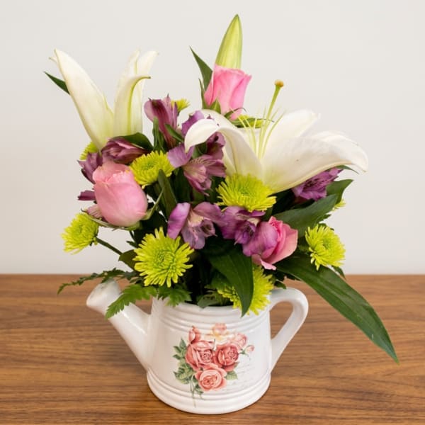 Mixed bouquet in a white watering can with pink, white, and purple flowers