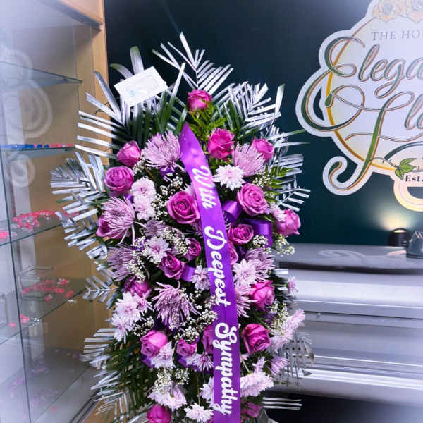 Standing spray of purple roses and lavender mums with a sympathy ribbon