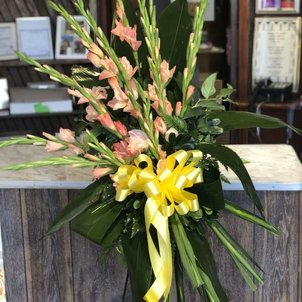 Tall floral spray with peach gladiolus and a yellow ribbon