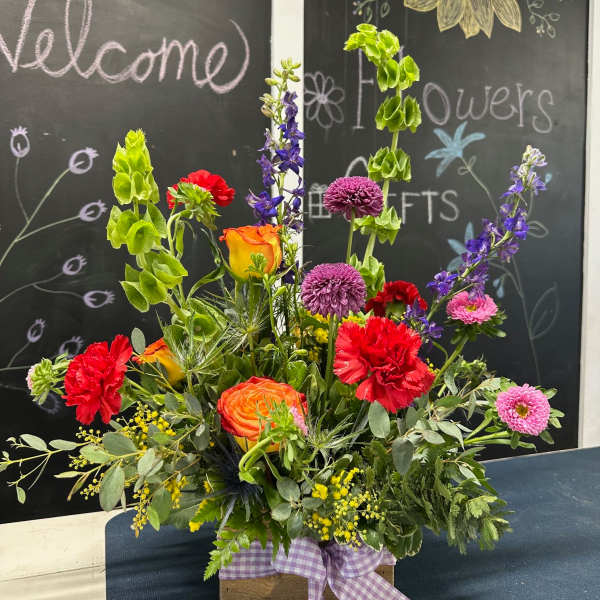 Colorful mixed flower arrangement in a wooden box with a purple ribbon