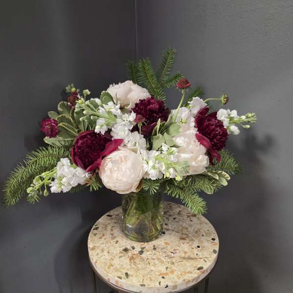 Bouquet of blush and burgundy flowers in a clear glass vase