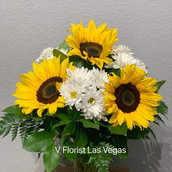 Medium vase arrangement of yellow sunflowers and white daisies in a clear glass vase