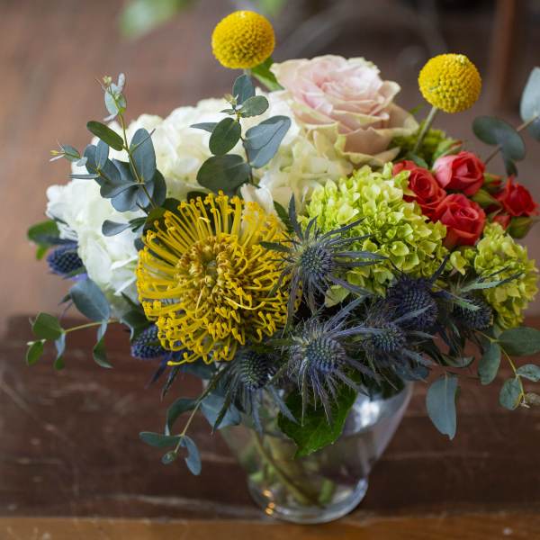 Mixed bouquet in a clear glass vase with yellow, white, pink, and red blooms