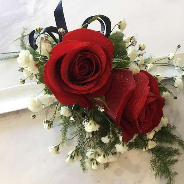 Red rose corsage with white baby's breath on a white ribbon