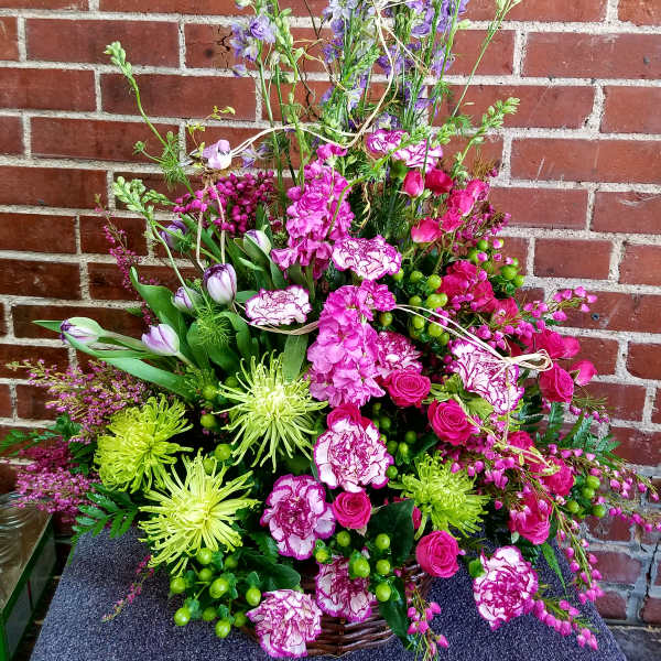 Tall basket arrangement with pink blooms, green spider mums, purple delphinium, and tulips