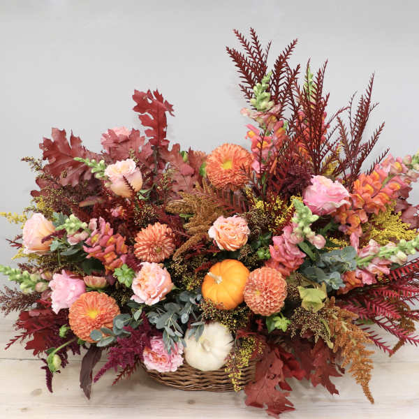 Autumn floral arrangement in a wicker basket with orange and pink blooms