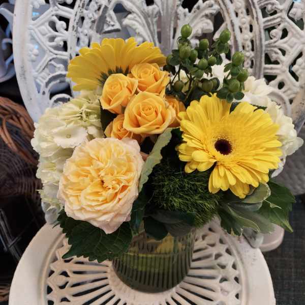 Yellow and peach flowers arranged in a glass vase