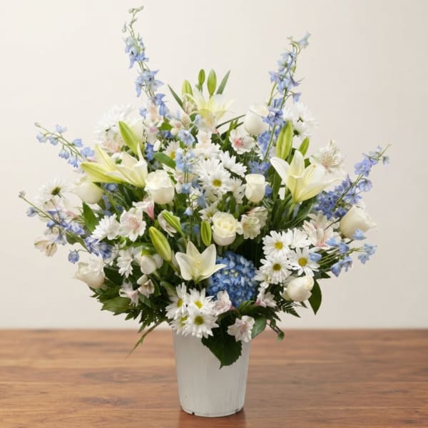 White and blue mixed flower arrangement in a white vase