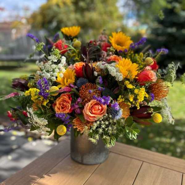 Colorful mixed bouquet in a metal vase on a wooden table