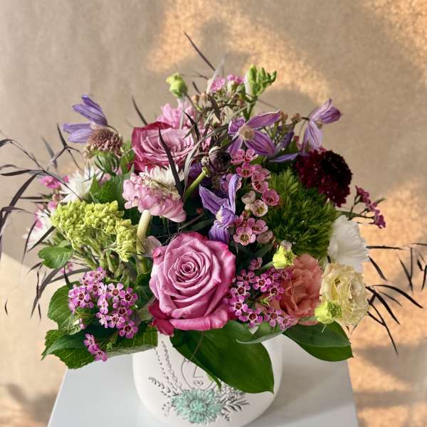 Pink and purple mixed flower arrangement in a white vase