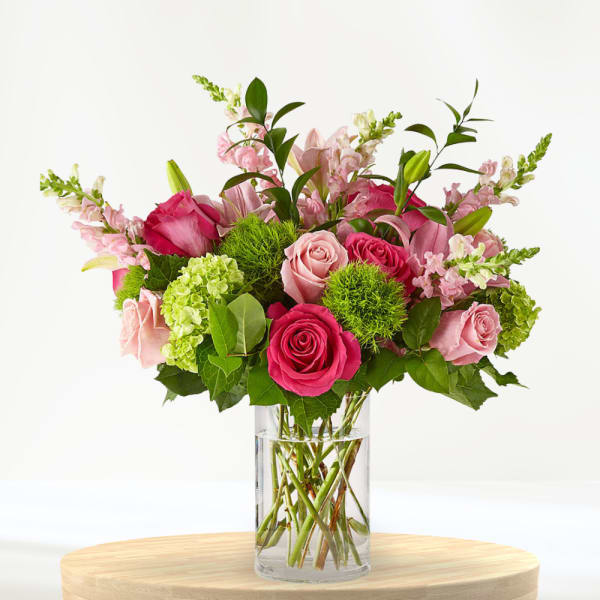 Pink roses and lilies arranged in a clear glass vase
