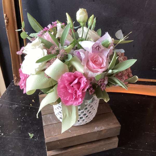Pink and white flower arrangement in a white vase with ribbon