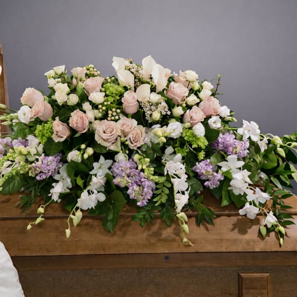 Pastel floral casket spray with roses, lilies, and orchids
