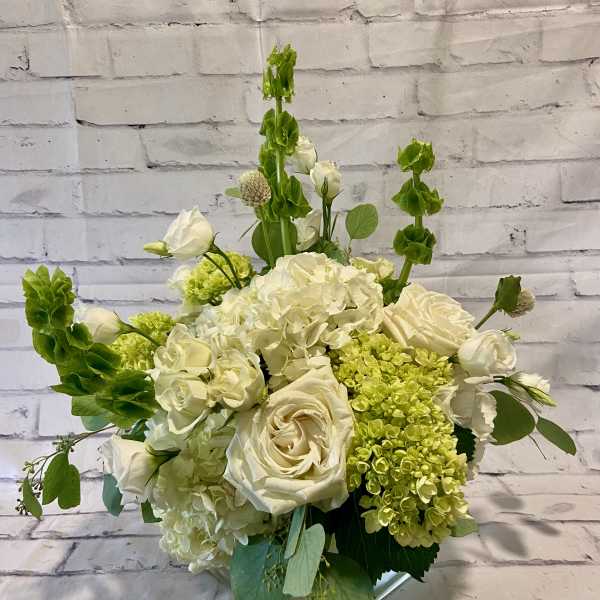 White roses and hydrangeas with green accent flowers in a vase
