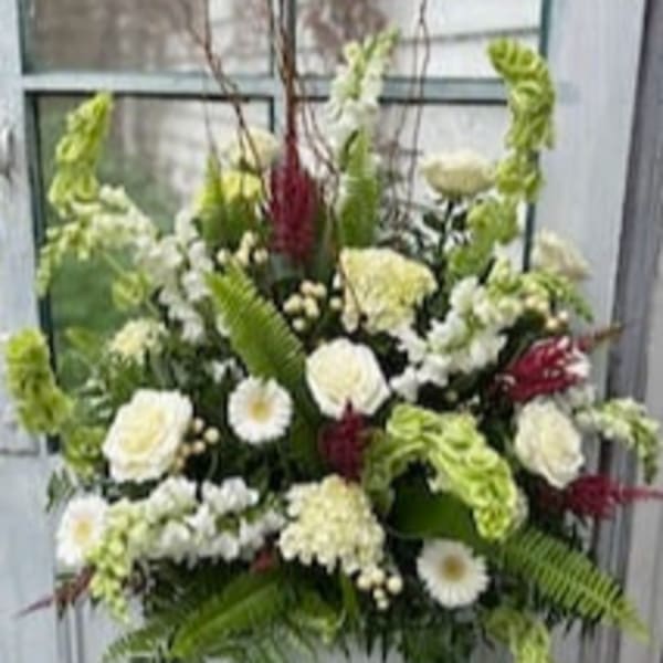 Large white and green floral arrangement in a white vase