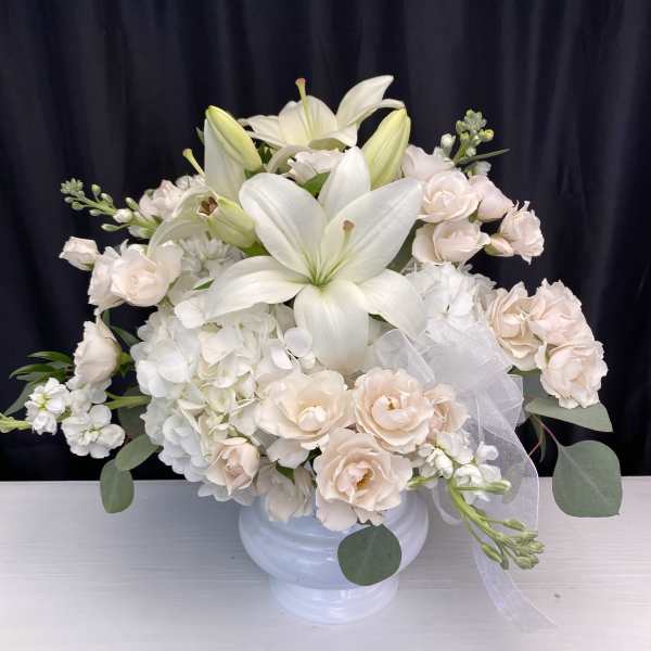 White lilies and pale blush roses in a white vase