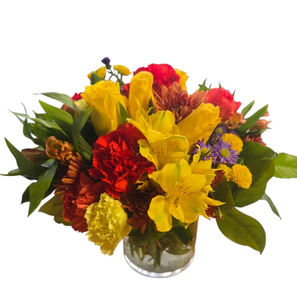Mixed bouquet of yellow, red, and purple flowers in a glass vase