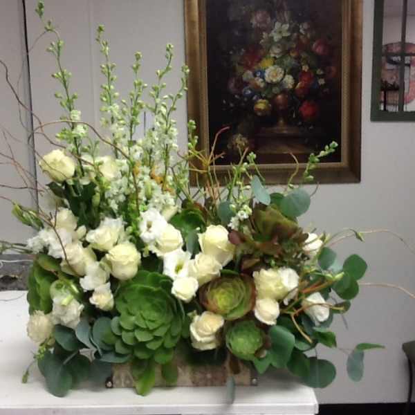White roses and green succulents in a low rectangular arrangement