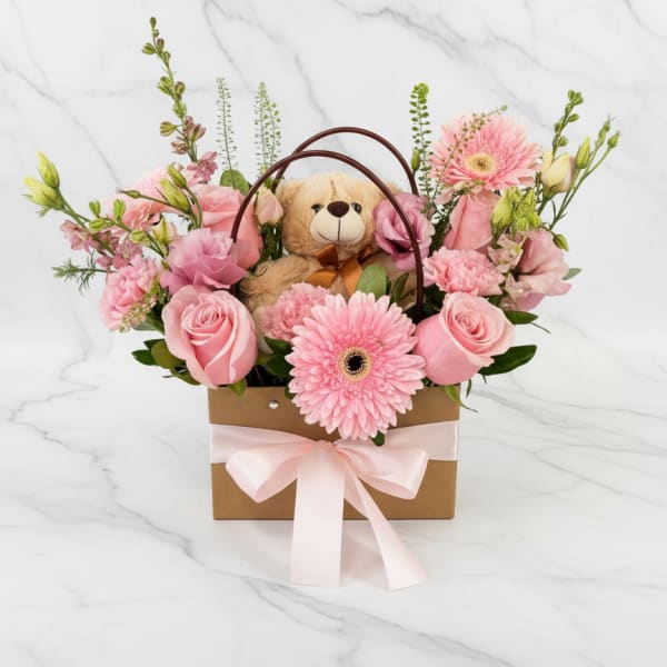 Pink flower basket with a teddy bear and ribbon
