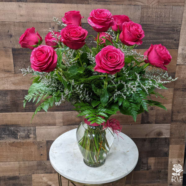 Pink roses arranged in a clear glass vase with greenery