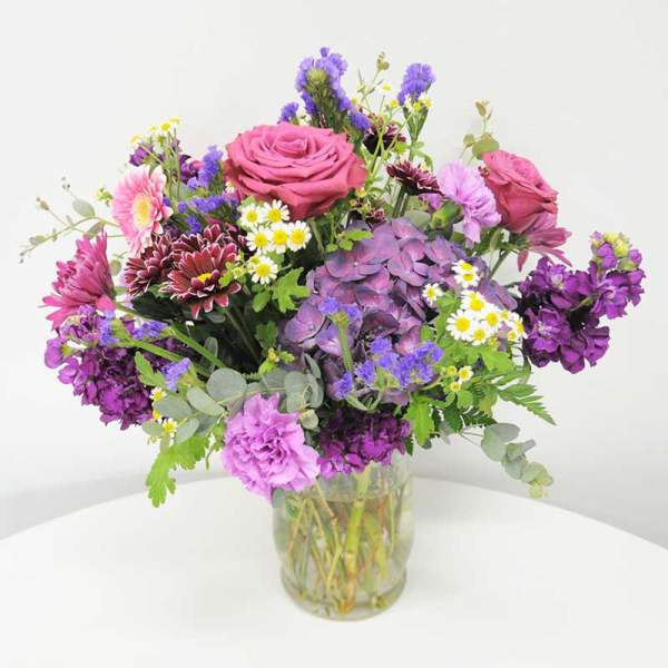 Mixed bouquet of pink and purple flowers in a clear glass vase