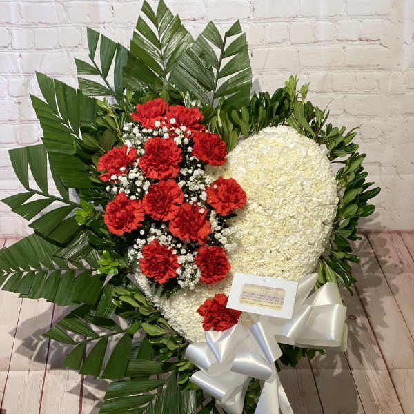 Heart-shaped floral wreath with red and white flowers and a white ribbon
