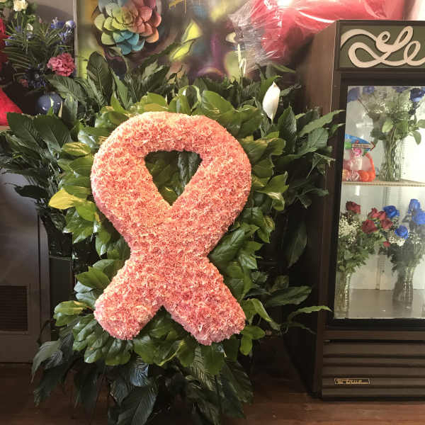 Pink floral awareness ribbon on a leafy standing display