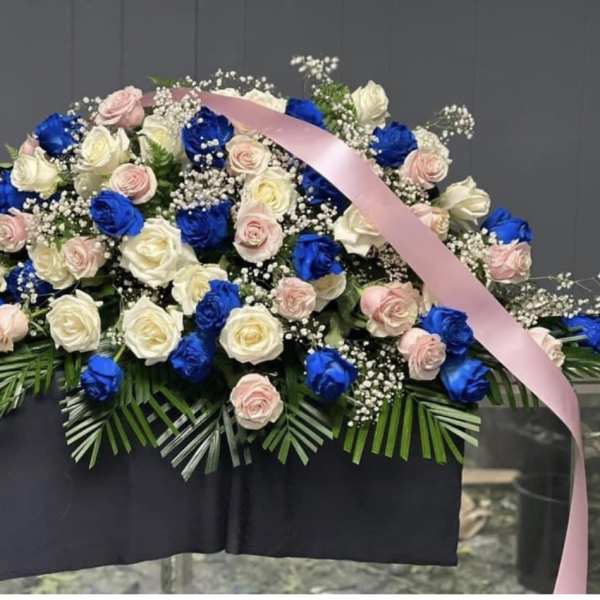 Large arrangement of blue, pink, and white roses with a pink ribbon