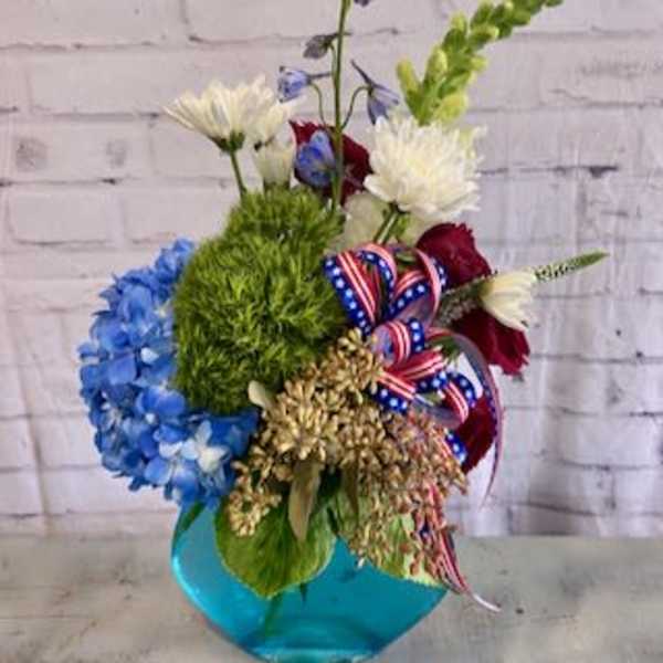Mixed bouquet with blue, white, red, and green flowers in a blue vase