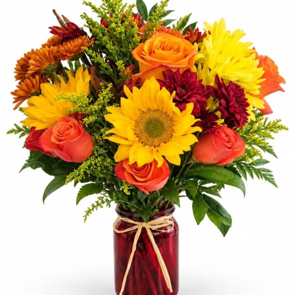 Bouquet of sunflowers, roses, and mums in a red glass vase