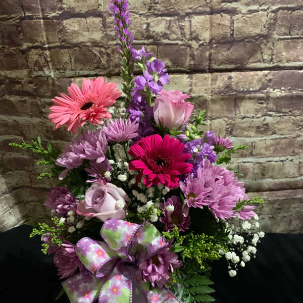 Pink and purple mixed flower arrangement with a floral ribbon bow