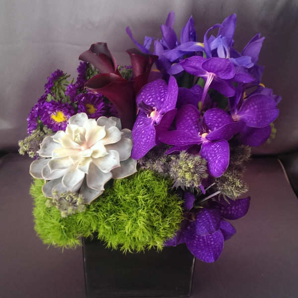 Purple orchids and calla lilies in a black square vase