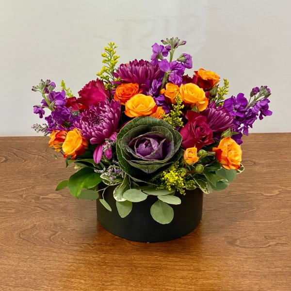 Colorful mixed flower arrangement in a black round box
