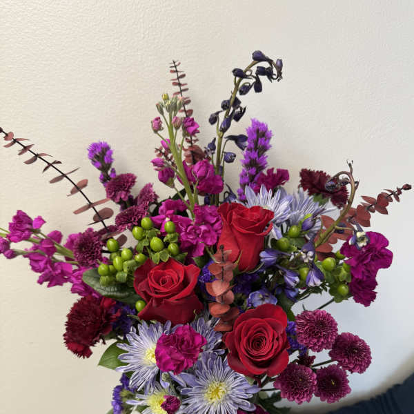 Bouquet of red roses, purple blooms, and lavender daisies