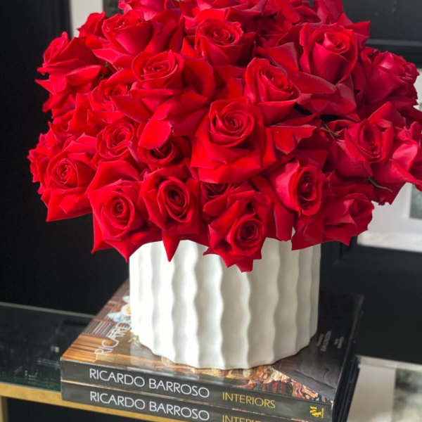 A bouquet of red roses in a white ribbed vase