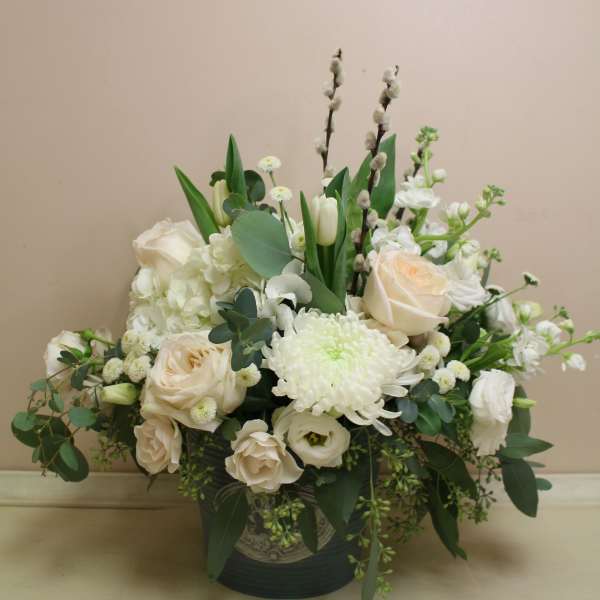 White floral arrangement in a dark vase with roses and chrysanthemums