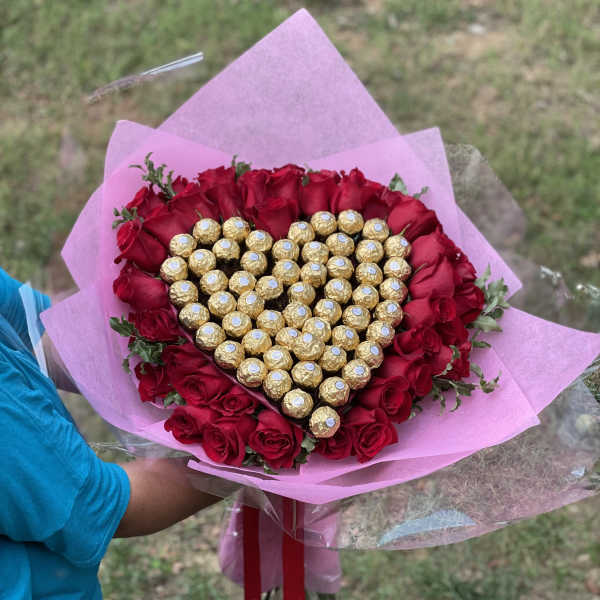Heart-shaped bouquet of red roses and gold-wrapped chocolates in pink paper