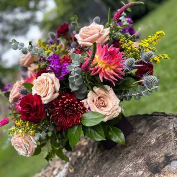 Bouquet of pink roses, burgundy blooms, and purple flowers