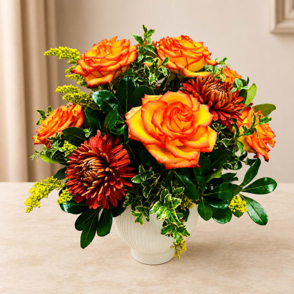 Orange roses and rust chrysanthemums in a white vase