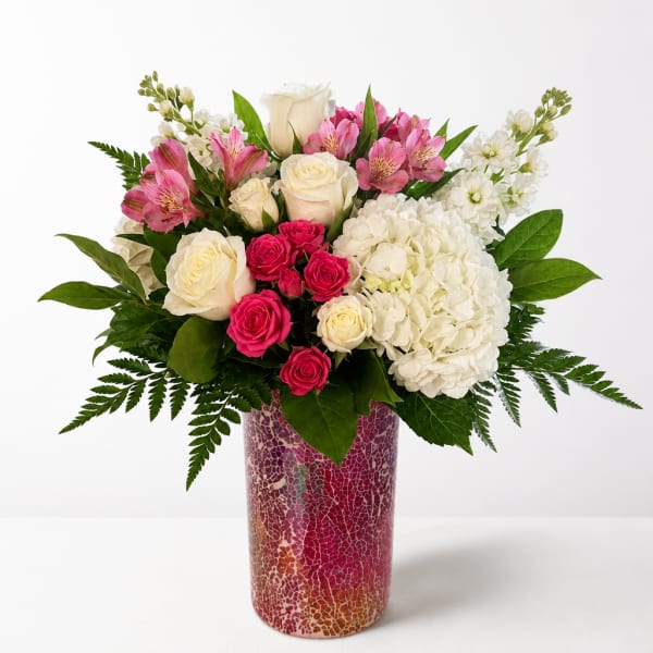 Pink and white flower arrangement in a tall patterned vase