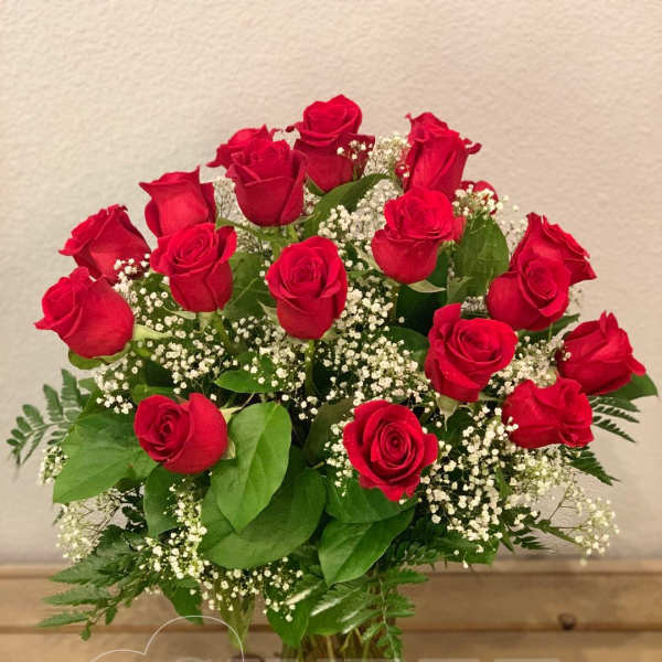 Bouquet of red roses with white baby's breath in a clear glass vase